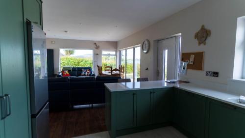a kitchen with green cabinets and a living room at Renard Haven - Cahersiveen in Cahersiveen