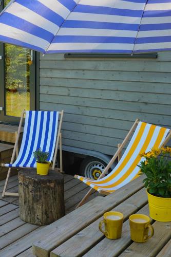 two chairs sitting on a deck under an umbrella at Prullenbos Tiny House Nutz Nest in Wetteren