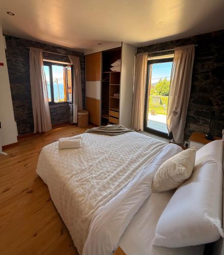 a large white bed in a room with two windows at Casa do terno com piscina in Arco da Calheta