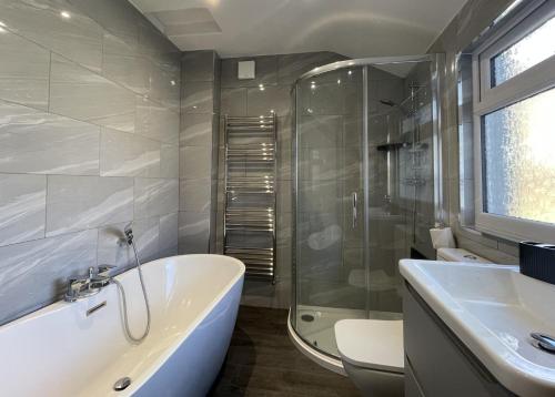 a bathroom with a tub and a sink and a shower at Ruby's Cottage in Threlkeld