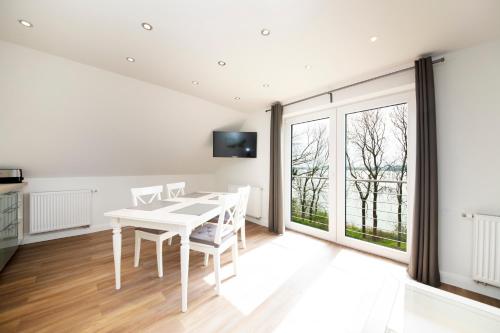 a white dining room with a white table and chairs at Appartement Schleipanorama in Rabenkirchen-Faulück