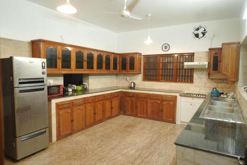 a kitchen with wooden cabinets and a stainless steel refrigerator at Pulimada Stays in Trichūr