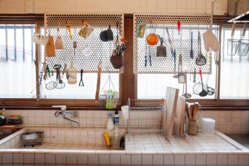 a kitchen with lots of utensils hanging on the wall at Guest House Maru in Kashima
