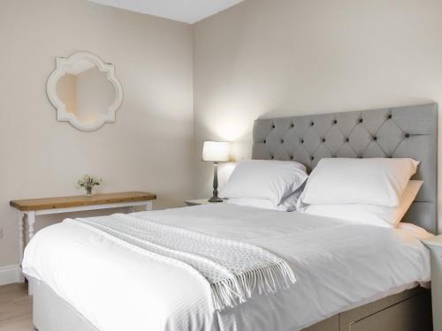 a bedroom with a large white bed with a silver headboard at Arthurs Cottage - Uk51636 in Kirkbean
