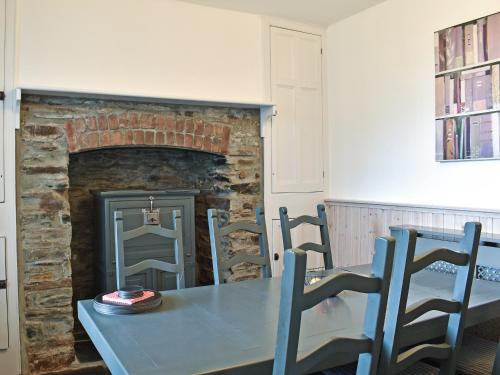a dining room with a table and a fireplace at Irisdene in Tintagel
