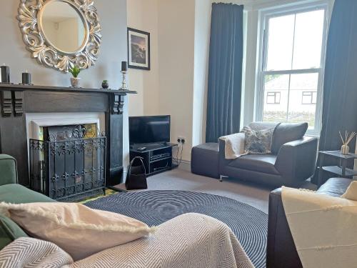 a living room with a fireplace and a mirror at Irisdene in Tintagel