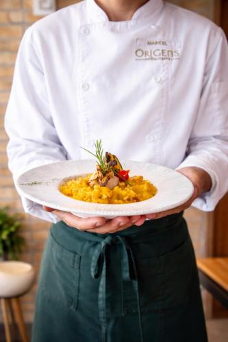 a chef is holding a plate of food at Quality Hotel & Suites Brasília in Brasília