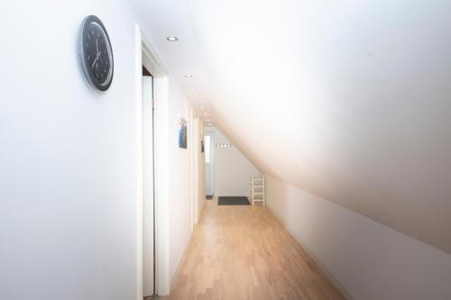 a long hallway with white walls and a clock on a wall at Schleitraum Appartement in Rabenkirchen-Faulück