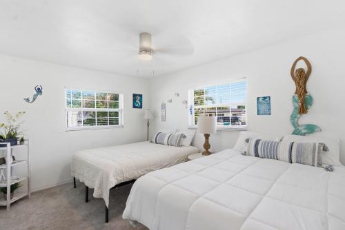 two beds in a room with white walls and windows at Spacious 4 bedroom 3 bath Clearwater Vacation House Cowboy Pool Fire Pit Games Close to Clearwater Beach Biking Trail Farmers Markets Harbor Health Spa Baycare Ballpark and Ruth Eckerd Hall Golf Courses in Clearwater