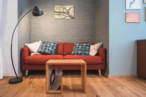 a living room with a red couch and a table at Oesenhof - Dielenwohnung in Bad Fallingbostel