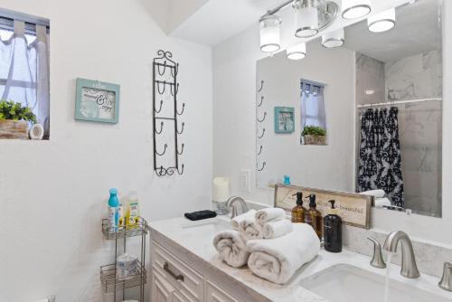 a white bathroom with a sink and a mirror at Spacious 4 bedroom 3 bath Clearwater Vacation House Cowboy Pool Fire Pit Games Close to Clearwater Beach Biking Trail Farmers Markets Harbor Health Spa Baycare Ballpark and Ruth Eckerd Hall Golf Courses in Clearwater