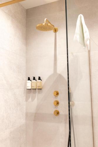 a bathroom with a shower with three bottles of soap at EL HOTEL - The Hague in The Hague