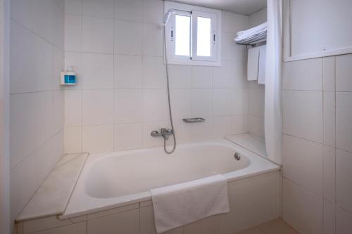 a white bathroom with a tub and a window at Hotel GHT Simeon in Tossa de Mar