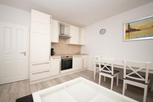 a kitchen with white cabinets and a dining room table at Schleiblick App 4 in Rabenkirchen-Faulück