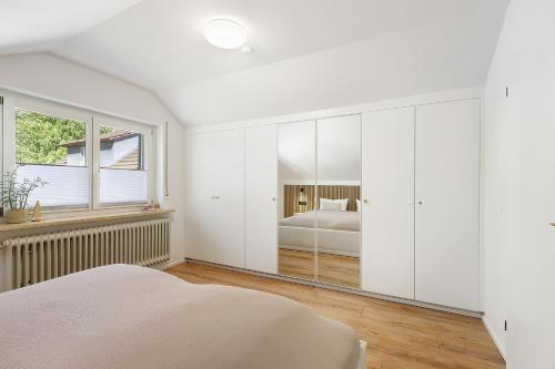 a white bedroom with a bed and a window at Hegauzauber in Tengen