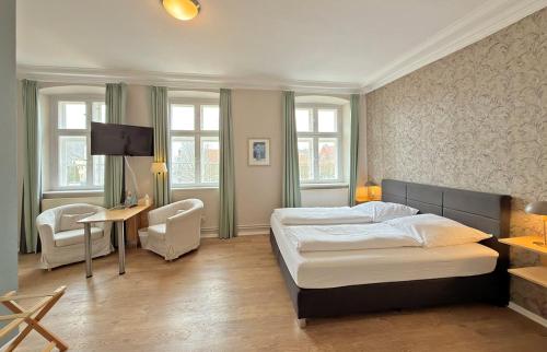 a bedroom with a bed and a table and chairs at Hotel Zollhaus in Schleswig