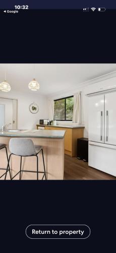 a kitchen with white cabinets and a counter with chairs at La Barca in Rye