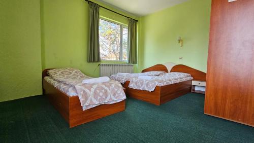 two beds in a green room with a window at Интернационал in Kulata