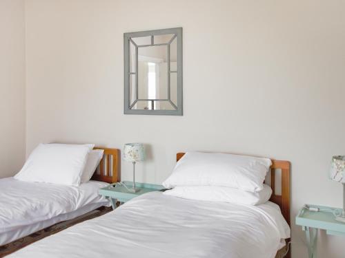 two beds in a room with a mirror on the wall at Beachcmbers Cottage - Uk51638 in Carsethorn