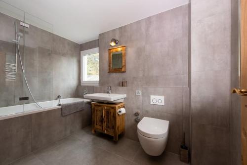 a bathroom with a toilet and a sink and a tub at Matterhorn Panorama Apartment in Zermatt