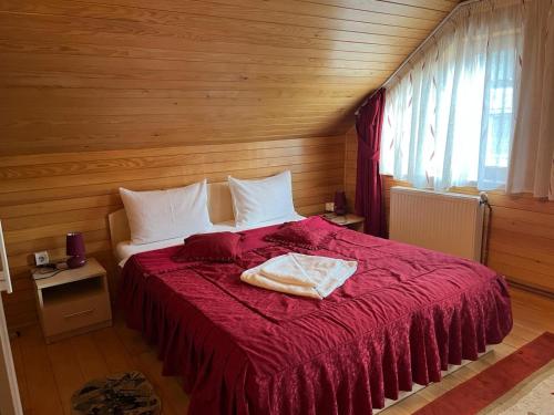 a bedroom with a large bed with a red blanket at Pensiunea Alexa in Durău