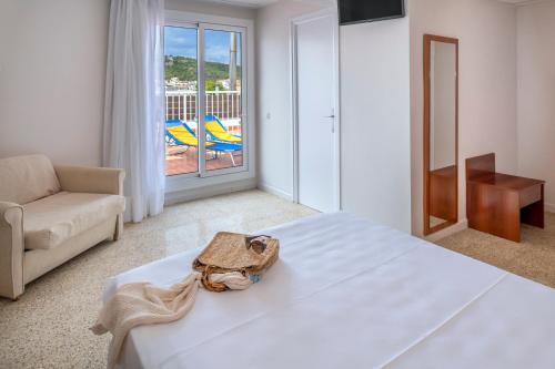 a bedroom with a bed and a couch and a balcony at Hotel GHT Simeon in Tossa de Mar