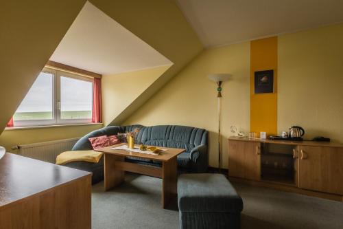 a living room with a couch and a table at Hotel-Pension am Rosarium in Sangerhausen