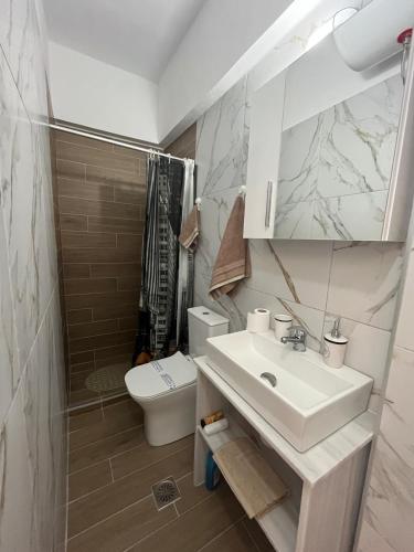 a white bathroom with a sink and a toilet at Beautiful apartment with mountain view in Paralio Astros