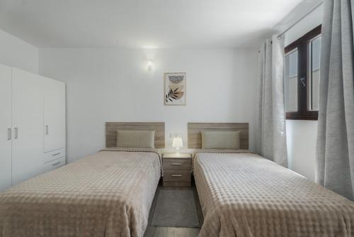 two beds in a bedroom with white walls and windows at El Barril in Chio