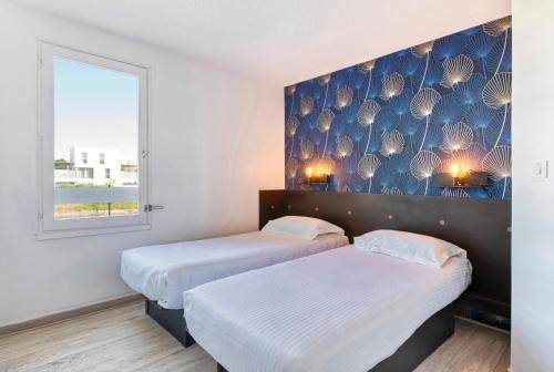 two beds in a room with a blue wall at Fasthotel Angers Beaucouzé in Beaucouzé