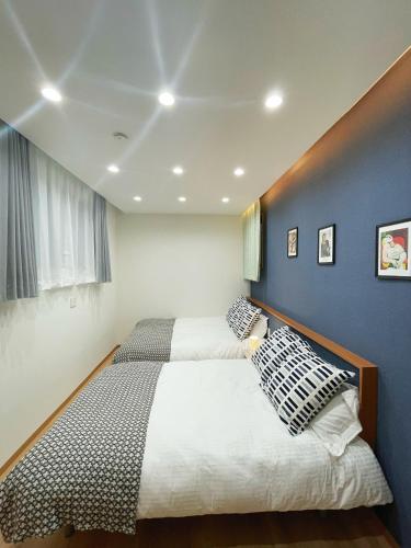 a bedroom with two beds and a blue wall at K-House in Tokyo