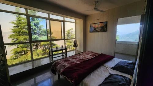 a bedroom with a bed and a large window at ONHILLs in Mussoorie