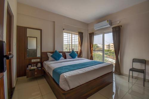 a bedroom with a bed with blue pillows and a window at AVN Comforts Mysore in Mysore