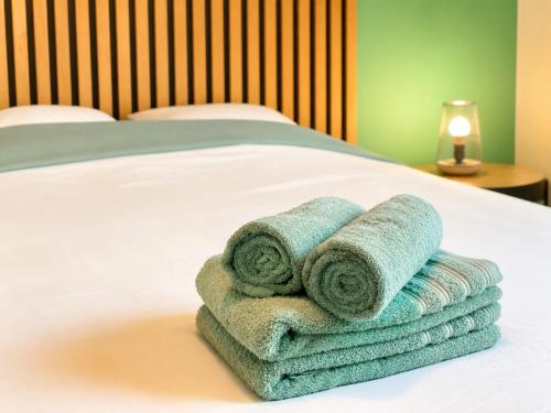 a pile of towels sitting on top of a bed at " Souffle Vert " Wifi - TV - 4 personnes in Muret