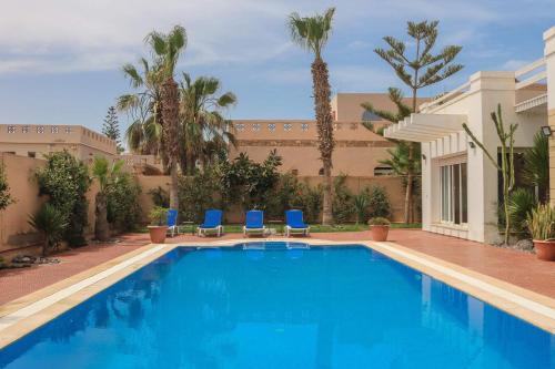 a swimming pool with blue chairs and palm trees at Spacious 3 bed 2 bath villa with Garden and Pool in Mirleft