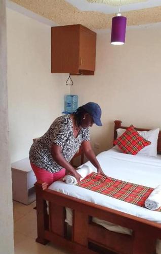 a woman kneeling on a bed in a room at Homebase gardens guesthouse in Nakuru