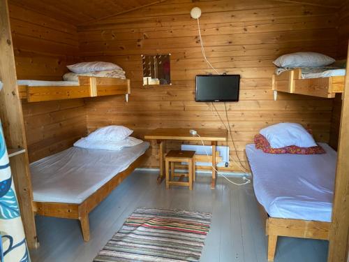a room with two beds and a table and a tv at Pirttiniemen Lomakylä in Muurasjärvi