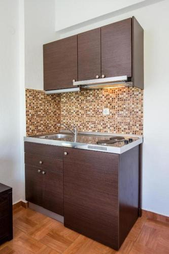 a kitchen with brown cabinets and a sink at Andronis in Potos