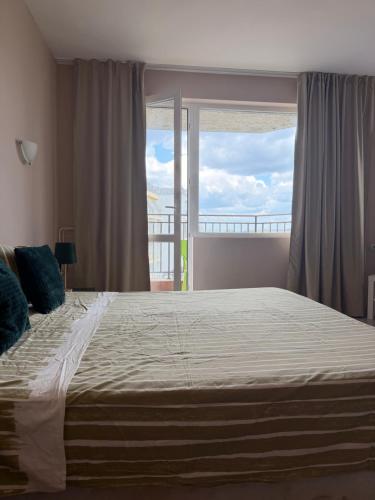 a bedroom with a large bed with a large window at Корал in Obzor
