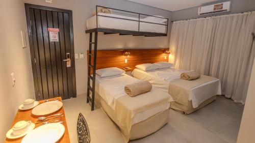 a hotel room with two beds and a table at Ap Passarela in Porto Seguro