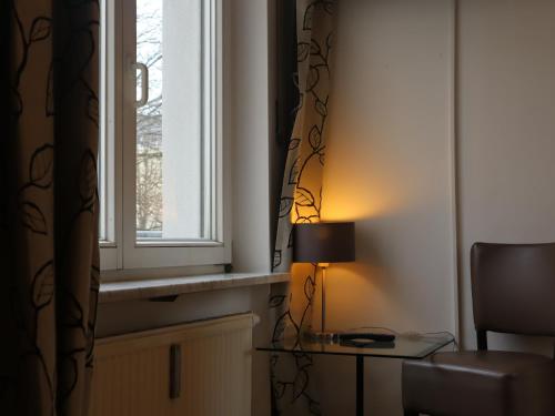 ein Zimmer mit Fenster und einem Tisch mit Lampe in der Unterkunft Hotel Prinz in München