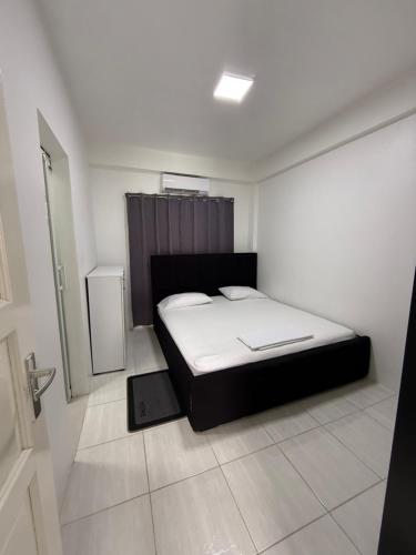 a bedroom with a bed in a white room at HHC Apartments Kronos in Paramaribo