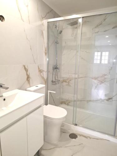 a white bathroom with a shower and a toilet at 4-As Andar-Moradia Muralhas in Guimarães