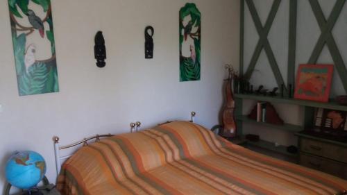 a bedroom with a bed and some pictures on the wall at MAISON d'Hôtes AFRIKA du QUEYROUX , petit gite en campagne proche BERGERAC, 1 seul animal accepté sur demande in Ginestet
