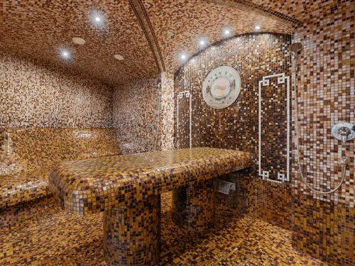 a tiled bathroom with a shower and a bench at Lielupe Hotel SPA & Conferences by Semarah in Jūrmala