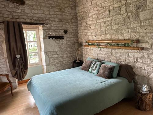 a bedroom with a bed in a stone wall at Domaine de pierre blanche in Pern