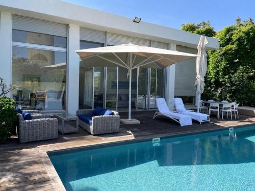 a pool with chairs and an umbrella next to a house at Beach House Galei in Herzliya B