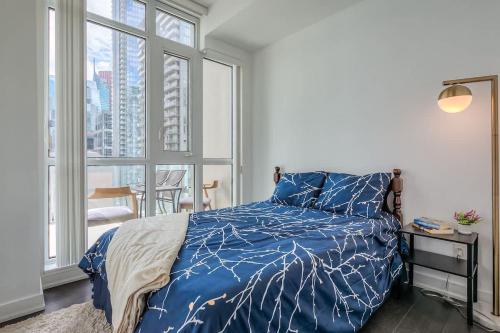 a bedroom with a blue bed and a window at CN Tower Views - 2BR Condo - Balcony - Fast Wi-Fi in Toronto