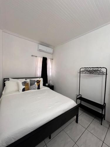a bedroom with a bed with white sheets and a window at Cozy Endz in Castries