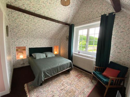 a bedroom with a bed and a window and a chair at Le clos du cèdre in Cellettes